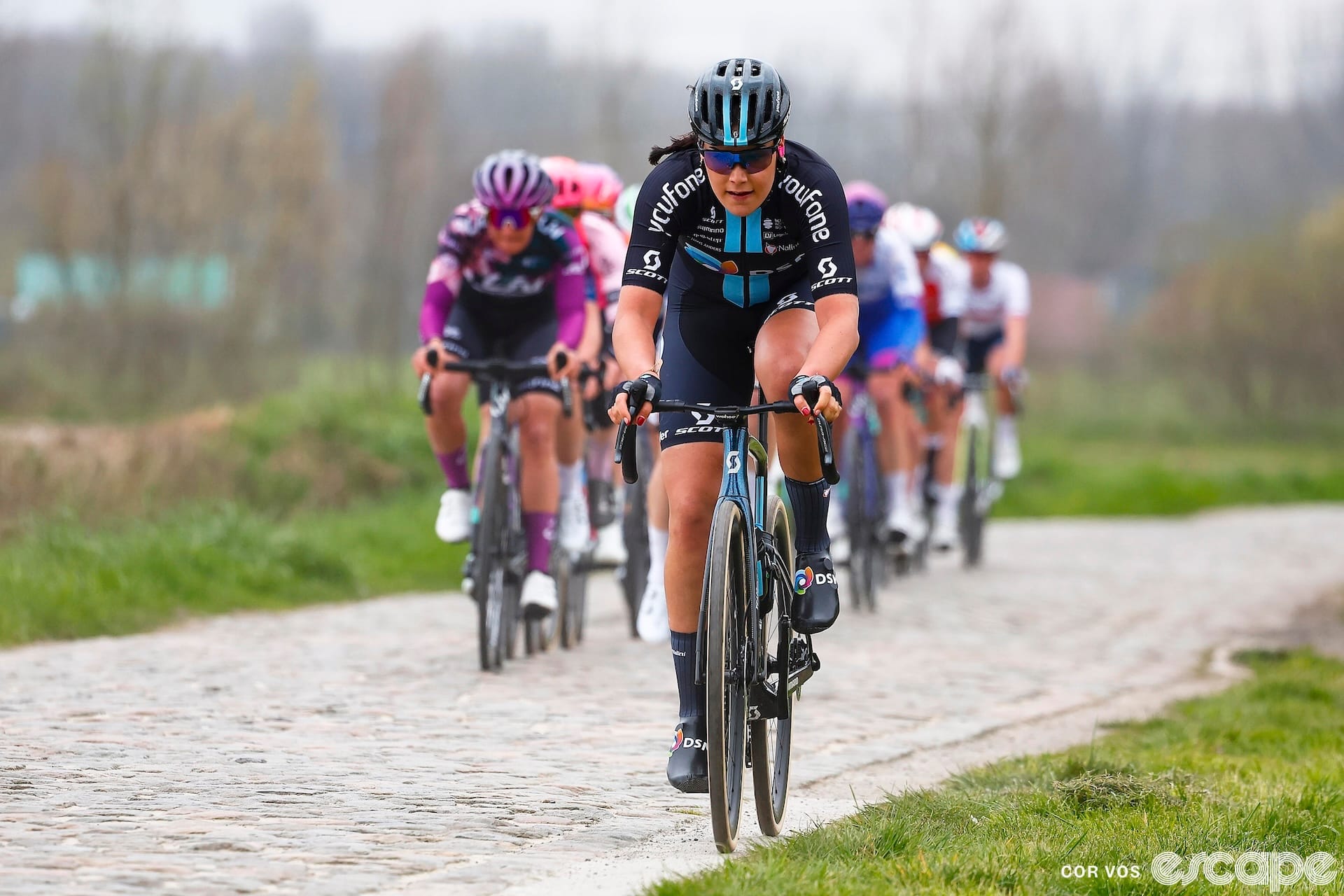 Daniek Hengeveld rides the Paris-Roubaix cobbles ahead of a line of pursuers.