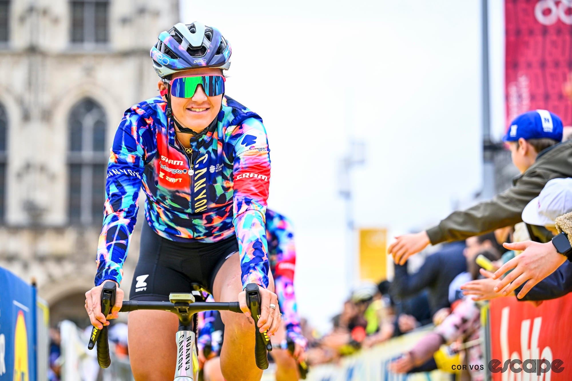 Dygert, in Canyon-SRAM kit, is pictured riding to the sign-in for the 2026 women's Tour of Flanders. The Oudenaarde city hall building is visible in the background.