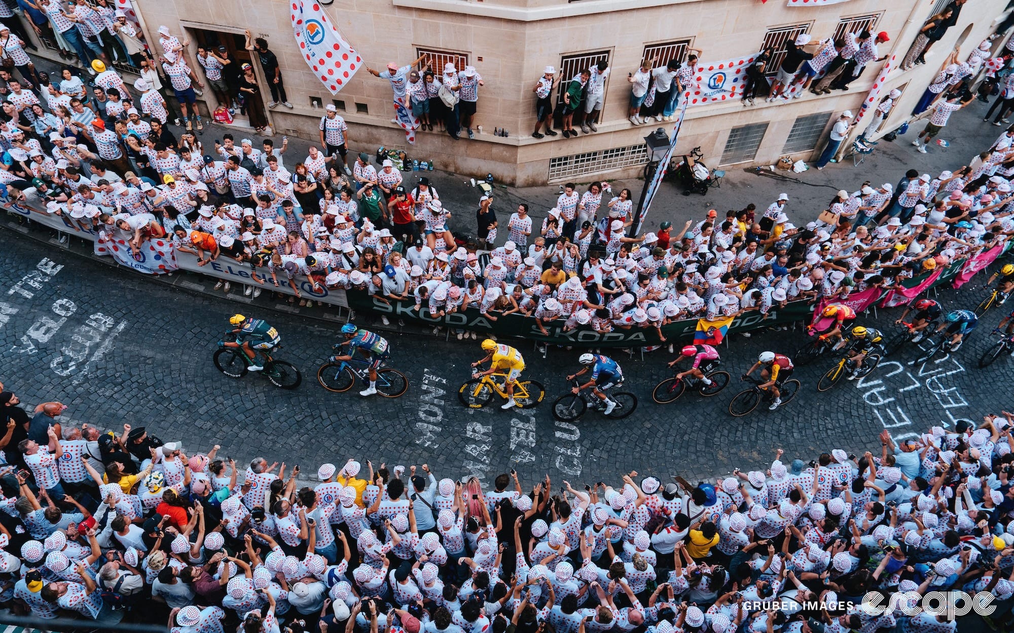 The peloton ascends the cobbles of Montmartre, marked with chalk, through deep crowds.