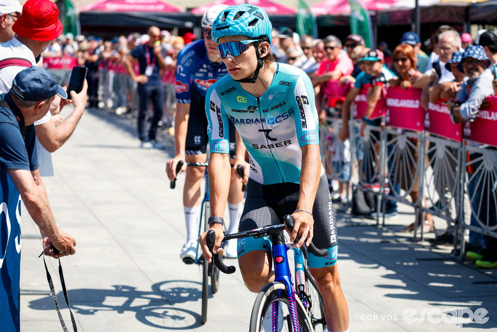 Nikita Tsvetkov is pictured in his Bardiani-CSF-7 Saber kit at the 2026 Giro. He is riding through the barriers to the start line past onlooking crowds.
