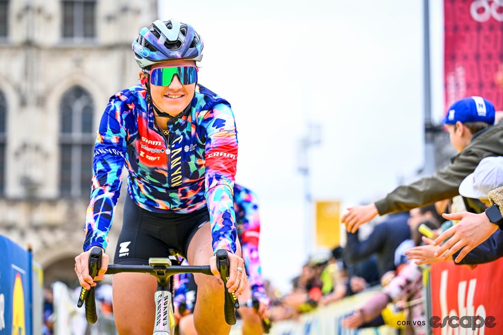 Dygert, in Canyon-SRAM kit, is pictured riding to the sign-in for the 2026 women's Tour of Flanders. The Oudenaarde city hall building is visible in the background.