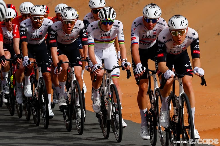 UAE riders in a paceline at the 2025 UAE Tour, outlined against a backdrop of red sand.