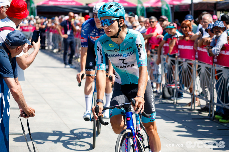 Nikita Tsvetkov is pictured in his Bardiani-CSF-7 Saber kit at the 2026 Giro. He is riding through the barriers to the start line past onlooking crowds.