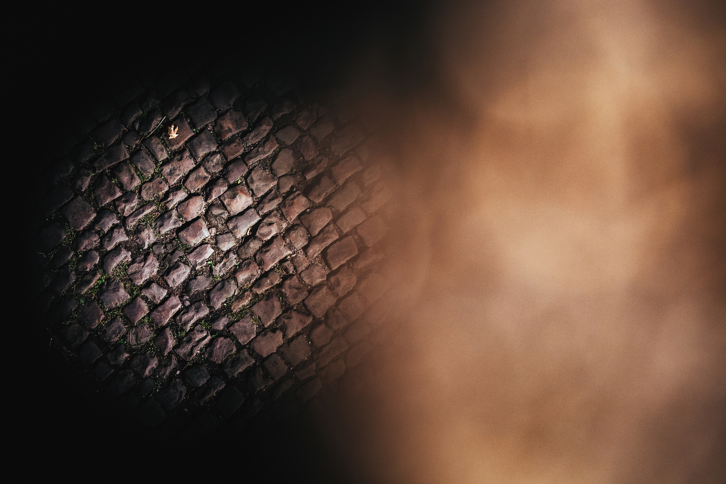 An artistic view of cobblestones, shot from above with a blurred, vignette-style framing.