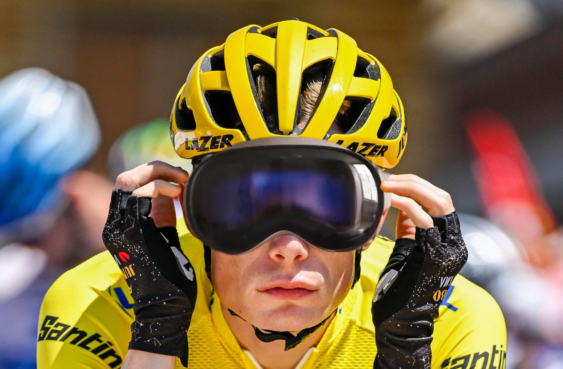 A photoshopped image of Jonas Vingegaard adjusting an Apple Vision Pro headset for a snug fit under his Lazer helmet