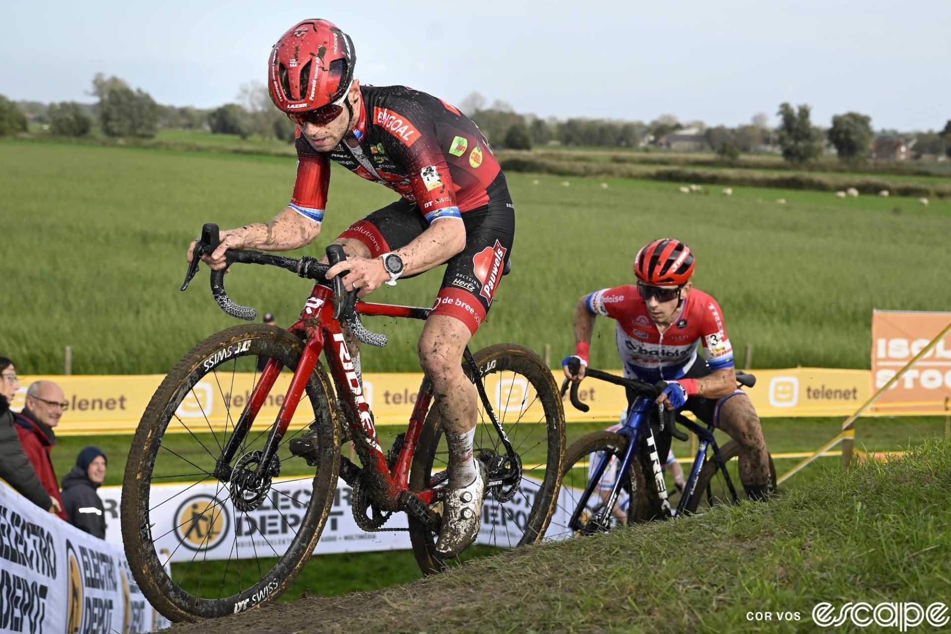 Eli Iserbyt crests a steep berm at Ruddervoorde. He's still clipped in and is past the top, while behind, Lars van der Haar is partly off the bike, a foot down and struggling to maintain momentum.