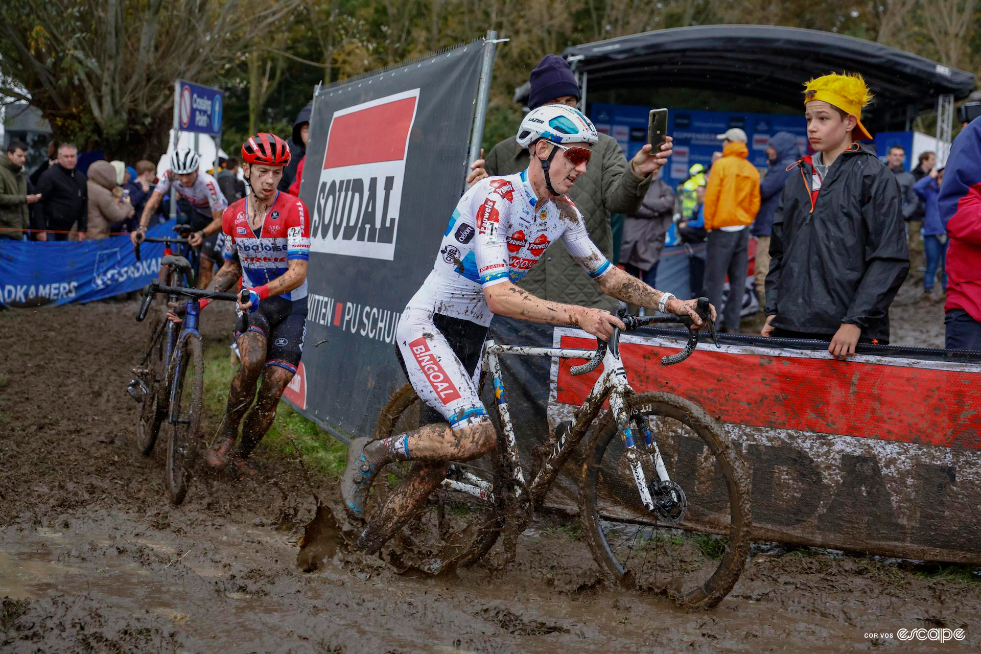 Michael Vanthourenhout leads Lars van der Haar during Koppenbergcross, both running alongside their bikes in the thick mud.