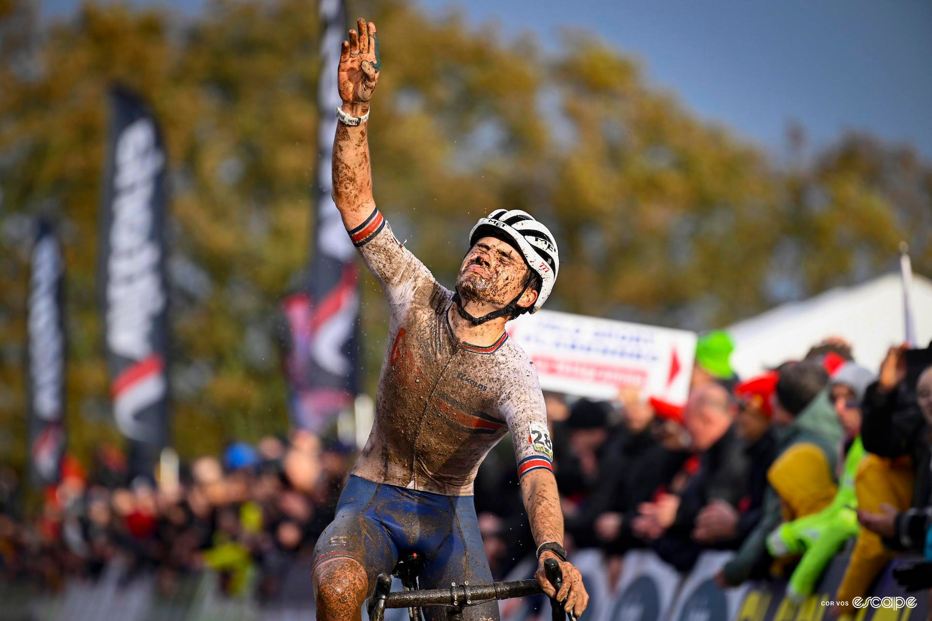 A mud-covered Cameron Mason crosses the finish line of the 2023 CX european champs in second place, pointing to the sky in an emotional tribute.