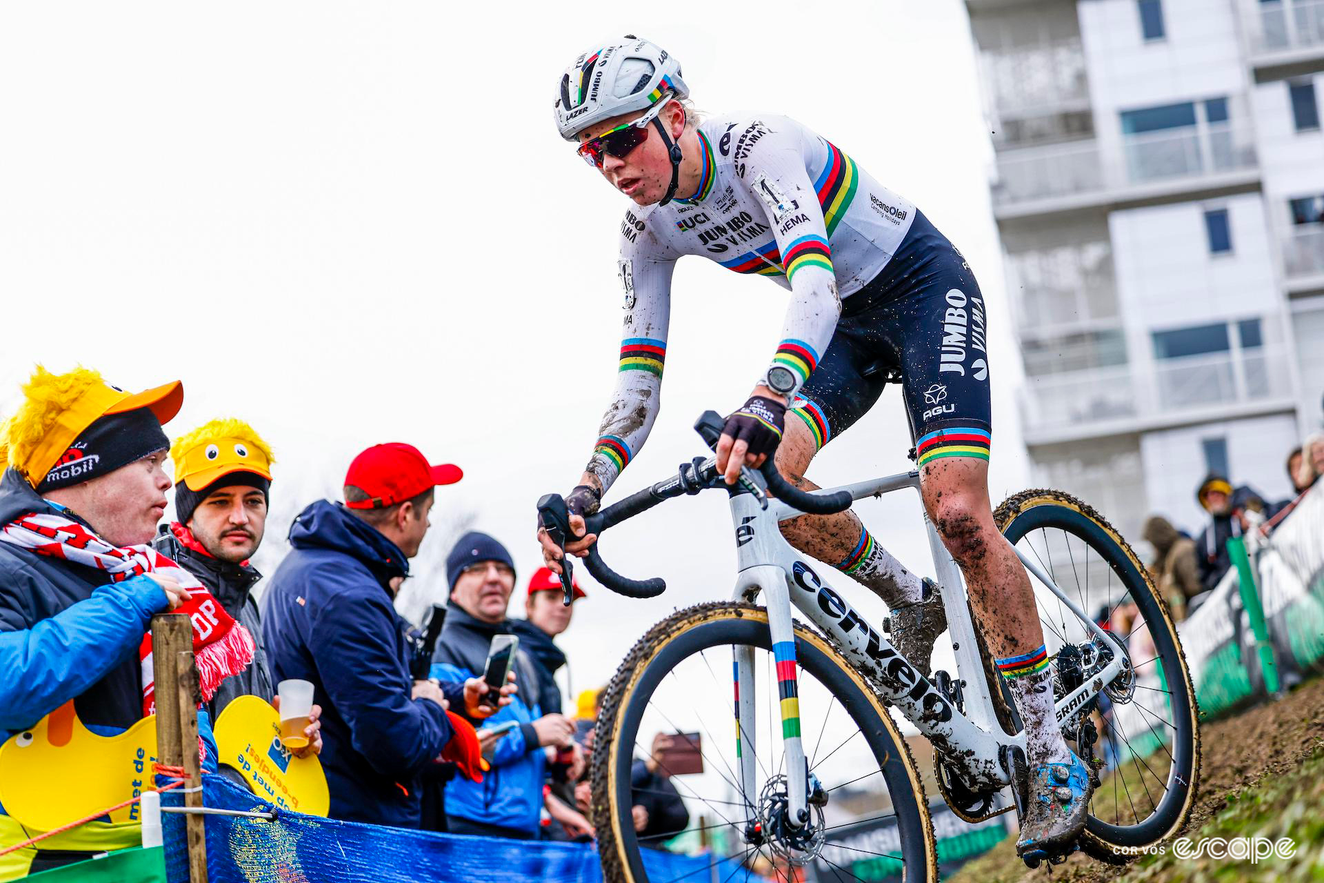 Head to toe in rainbow banded team kit, Fem van Empel rides solo out of the off-camber section during X20 Trofee Kortrijk as fans wearing X20-branded yellow duck memorabilia look on.