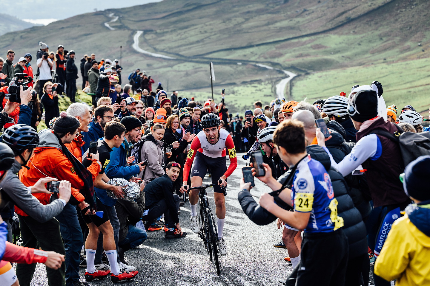 The image shows huge crowds cheering on Ed Laverack as he climbs "The Struggle" road in the 2023 British National Hillclimb championships.