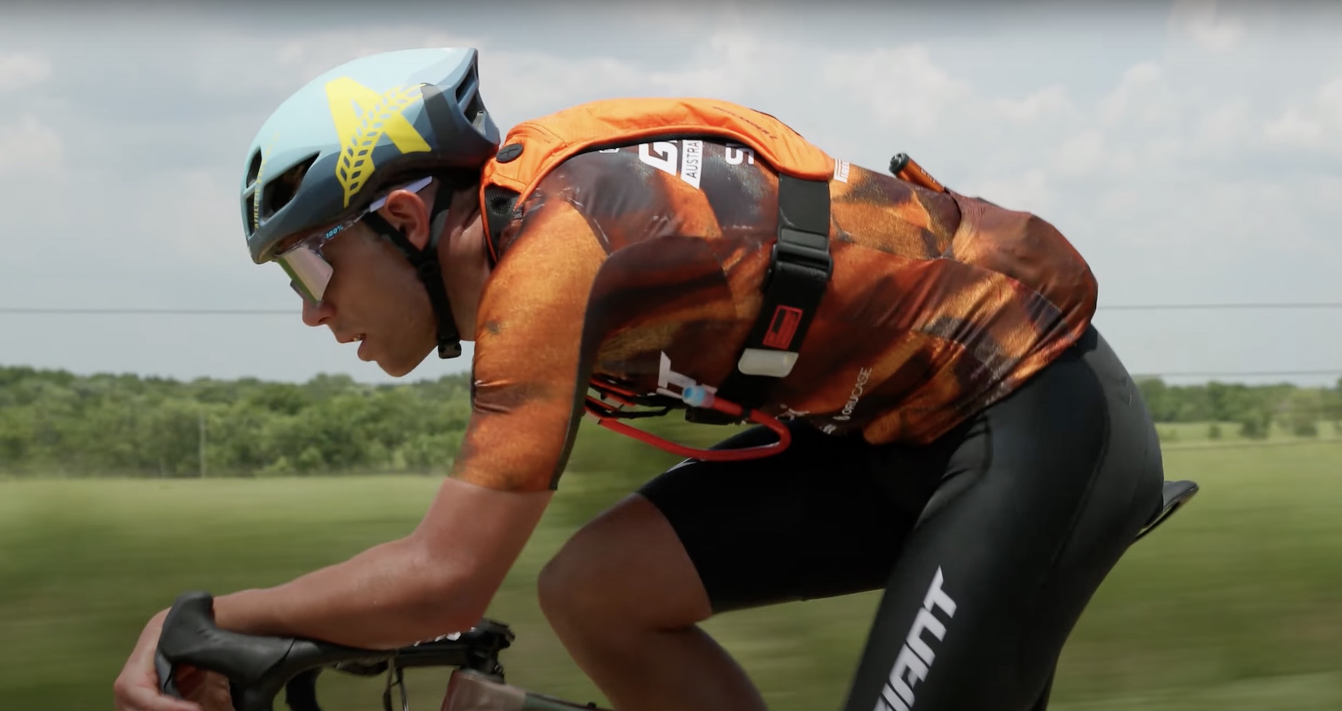 A side-on shot of Brendan Johnston riding along a gravel road with a hydration pack on his back.