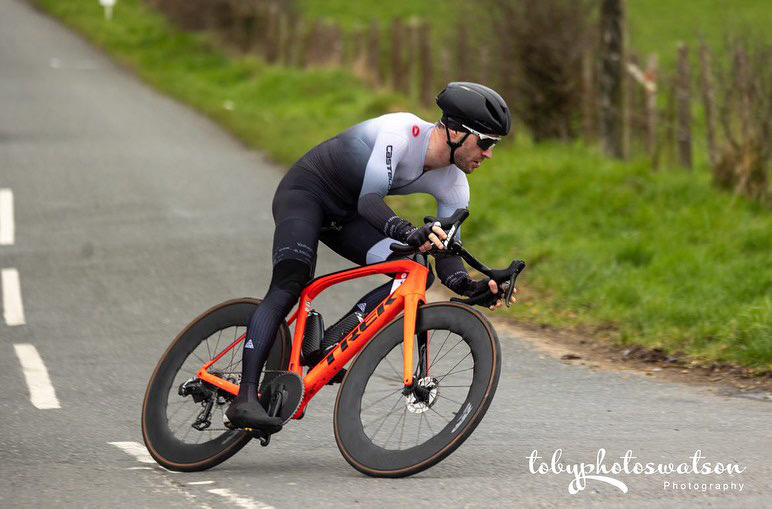 The photo shows Ronan Mc Laughlin cornering on a Trek Domane SLR in a road race.