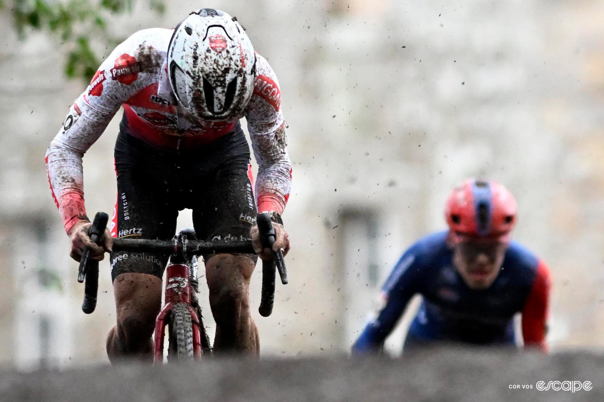 Eli Iserbyt in the World Cup leader's white jersey flicks up mud as he sprints away from Pim Ronhaar during Cyclocross World Cup Flamanville.