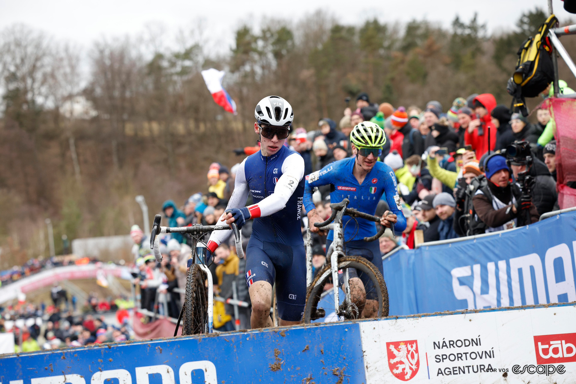 Early leaders of the junior men's race, Aubin Sparfel of France and Stefano Viezzi of Italy, leap over the planks on foot during the 2024 Cyclocross World Championships in Tábor.