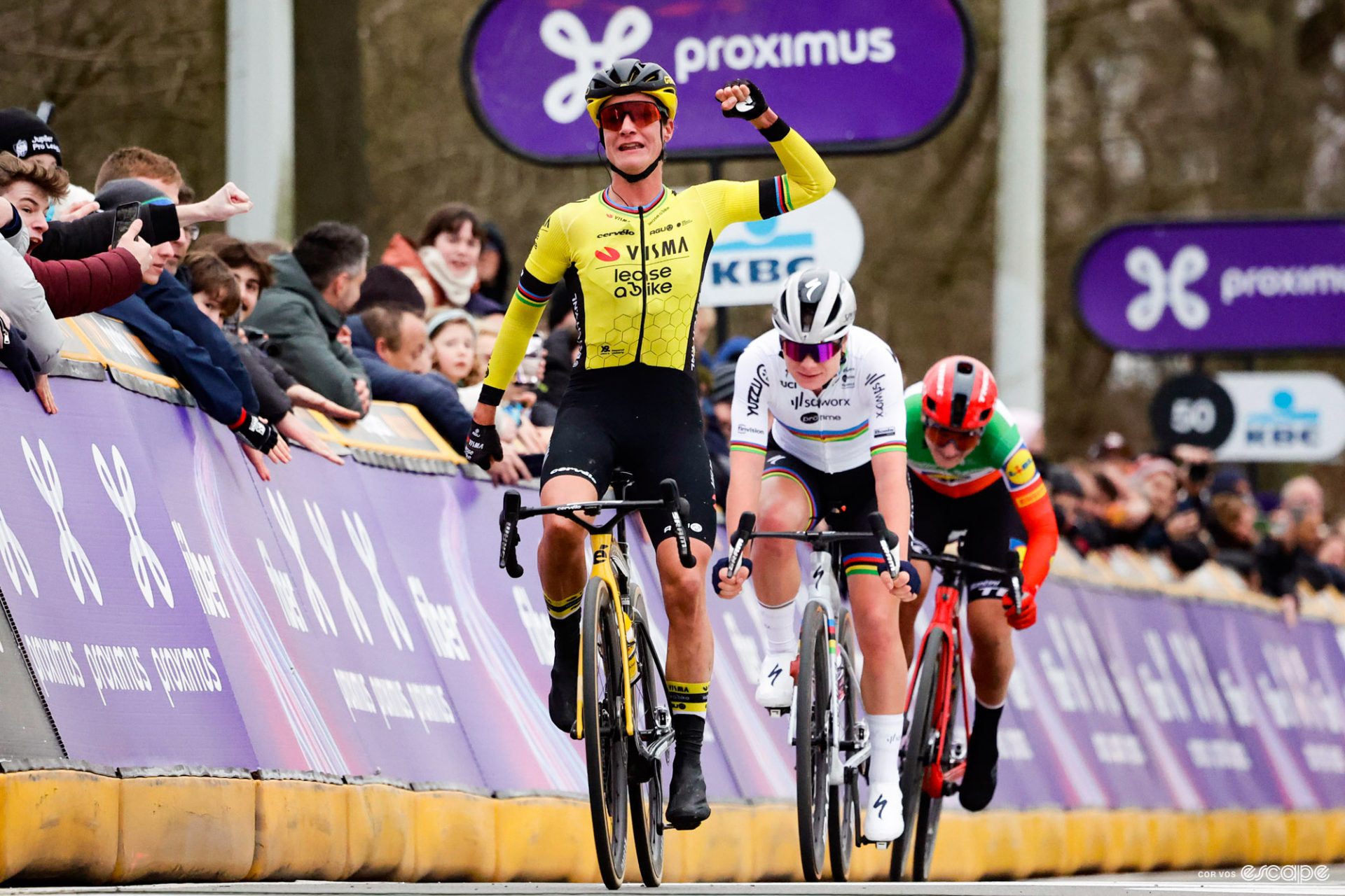 Mariane Vos sticks her hands in the air as she wins Omloop Het Nieuwsblad ahead of Lotte Kopecky and Elisa Longo Borghini.