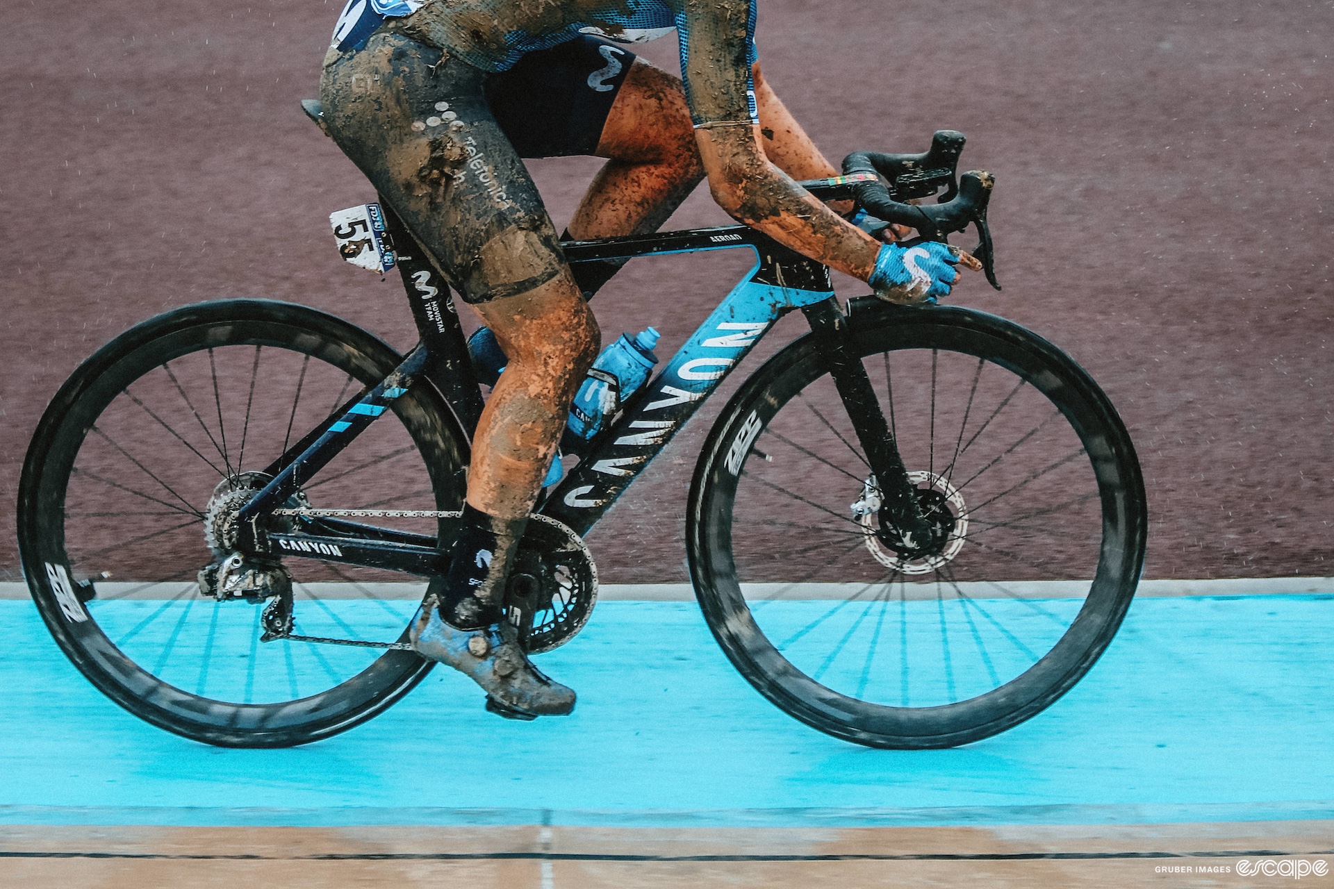 A side view of a woman's legs while riding a bike, covered in mud.