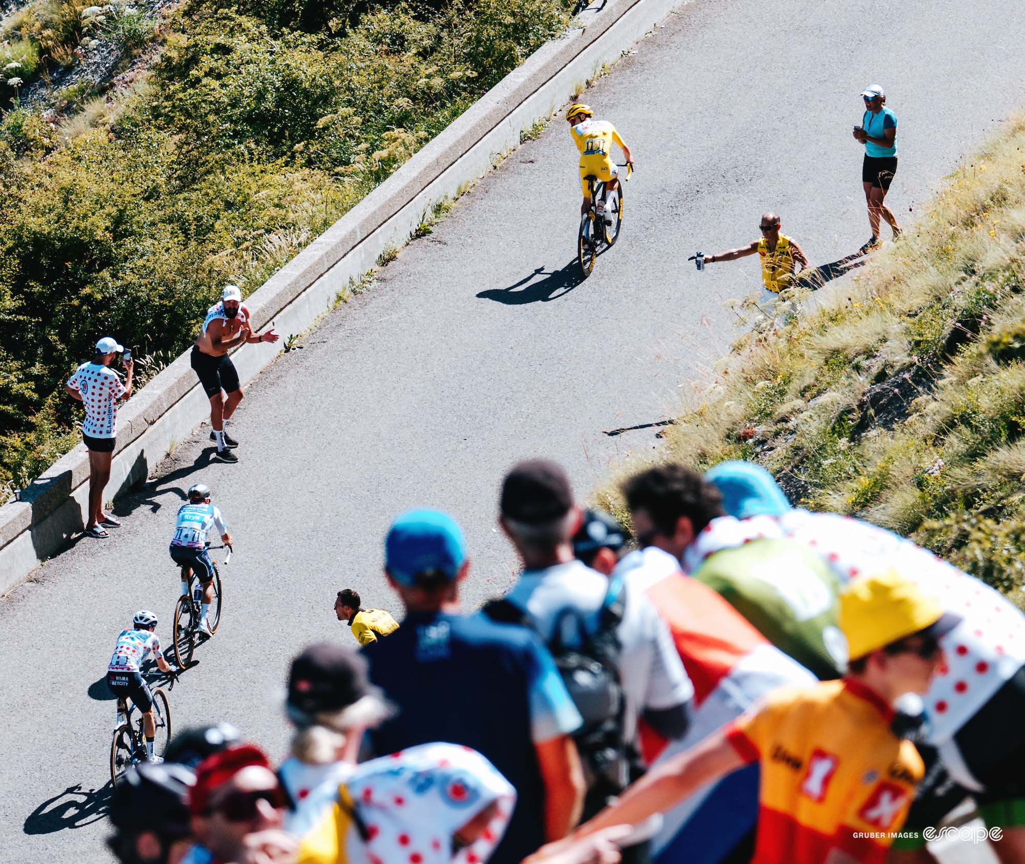 Tadej Pogačar attacks on a climb on stage 17 of the 2024 Tour de France. He is seen from high above, and has a gap and is looking back to see who follows him.