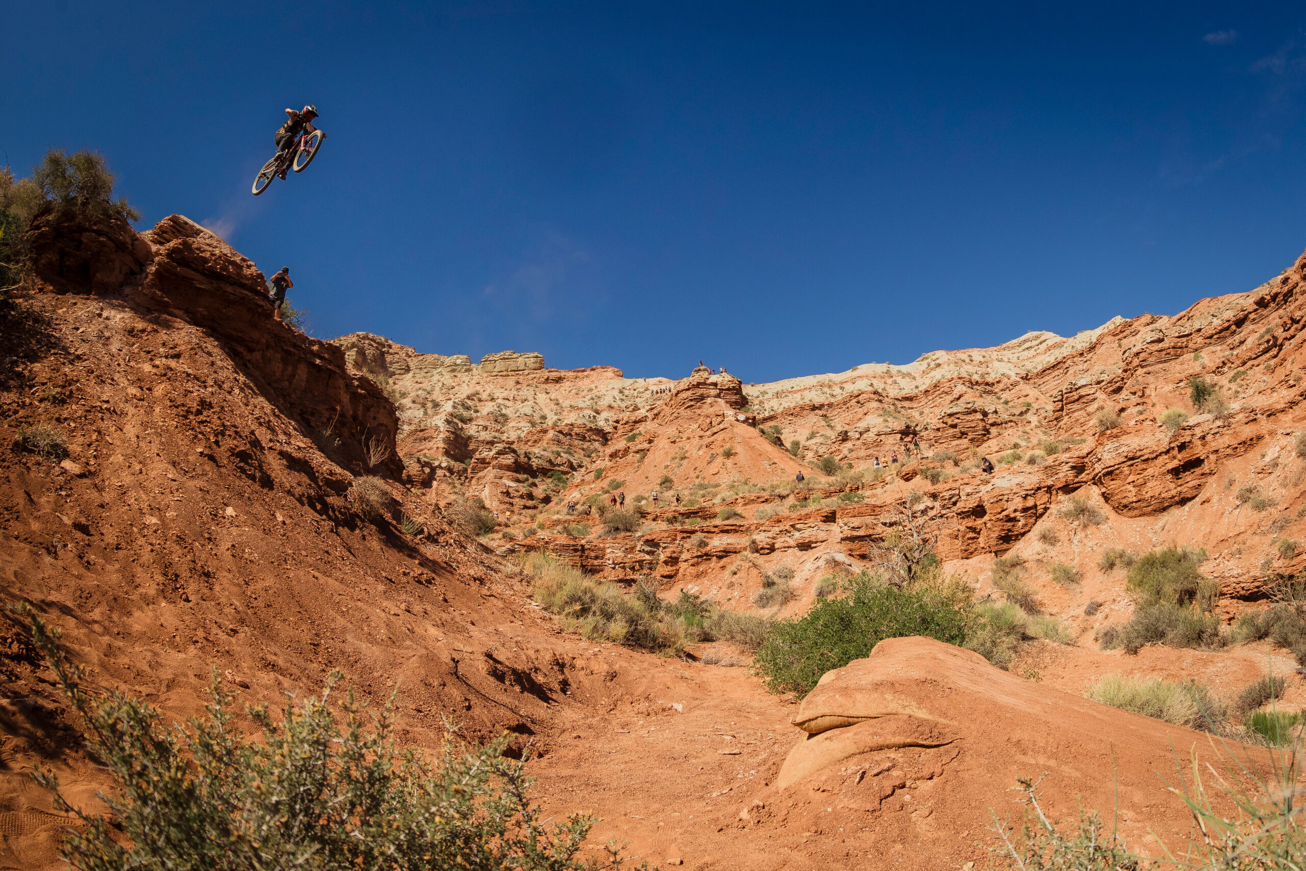 Camila Nogueira launches a takeoff of a massive jump in Red Bull Formation. Steep sandstone cliffs form a bowl around her, and she's easily 30 feet in the air as she soars above the camera toward a landing zone.