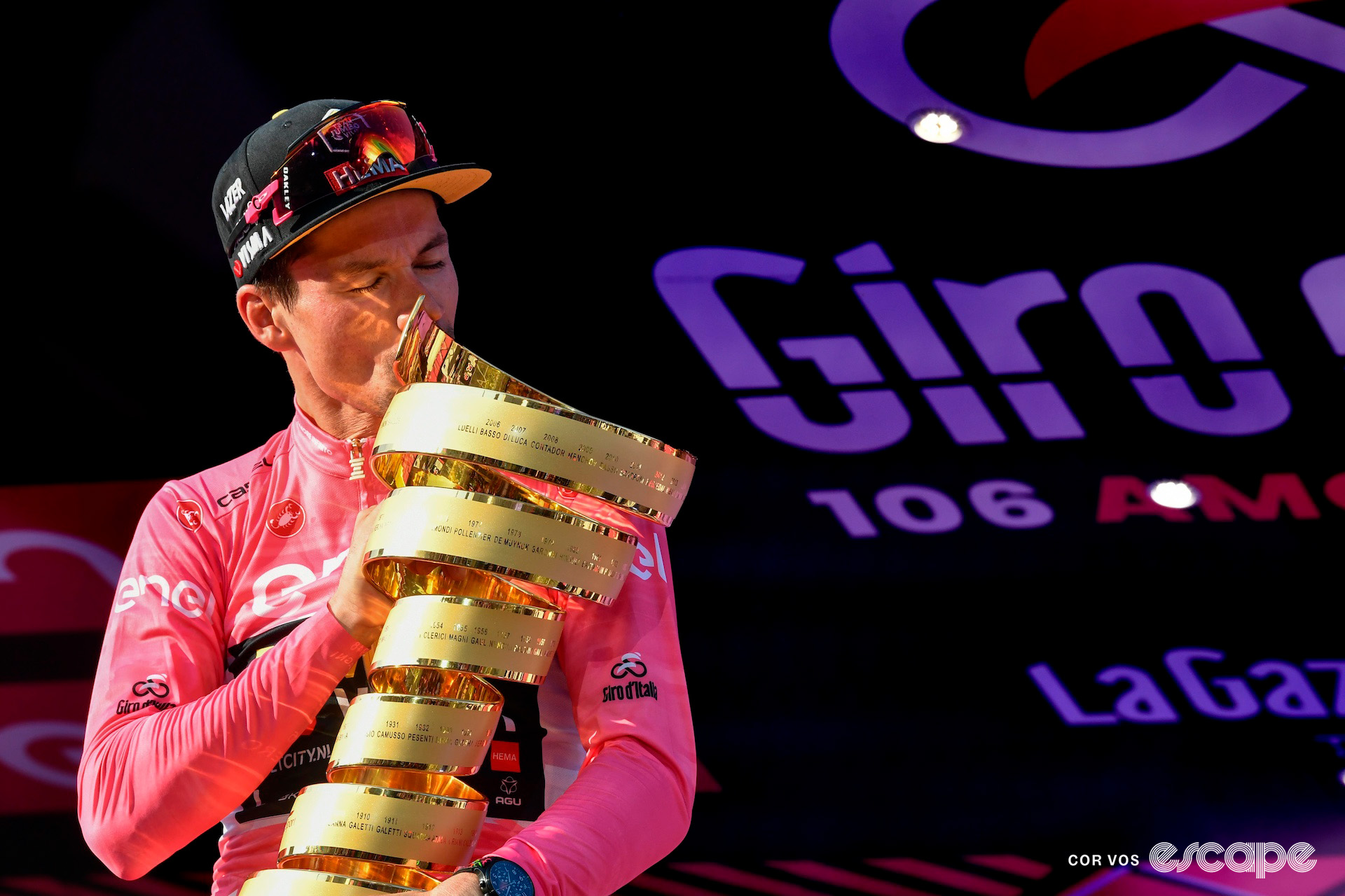 Primož Roglič, wearing the pink jersey, kisses the Giro d'Italia winner's trophy at the end of the 2023 edition.