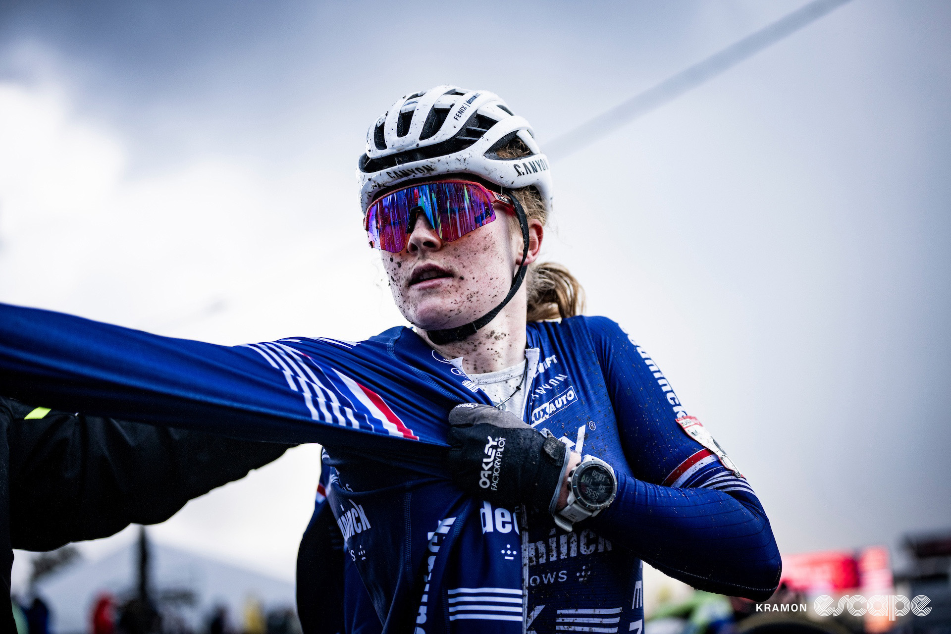 Puck Pieterse pulls on a jacket over her mud-splattered race kit after cyclocross World Cup Zonhoven.