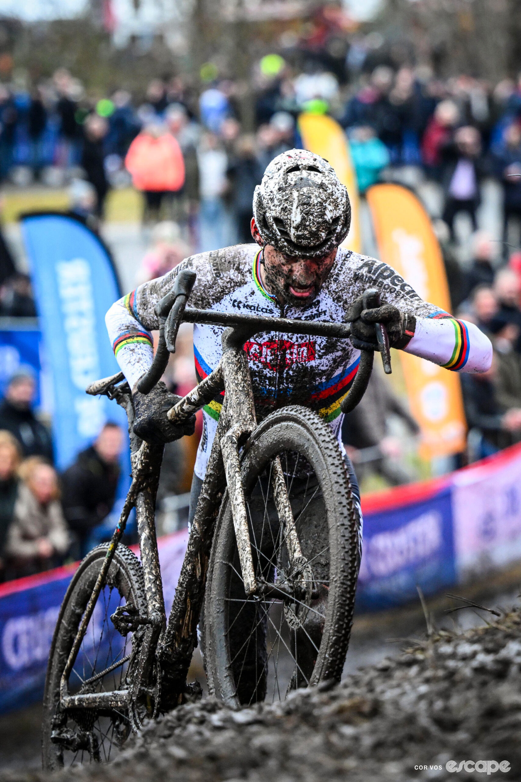 Mathieu van der Poel runs with his bike up a muddy banking during cyclocross World Cup Maasmechelen.