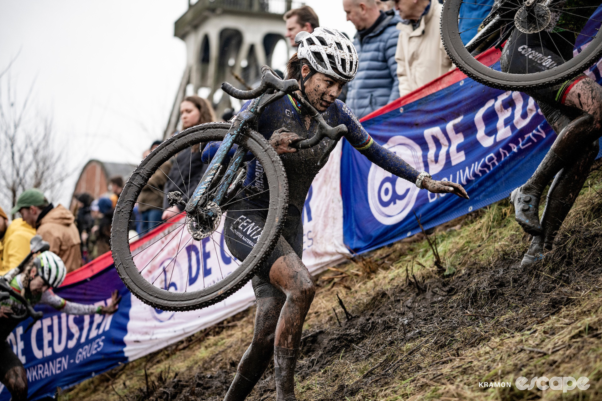 Celyin del Carmen Alvarado runs up a grassy bank with her bike on her shoulder during cyclocross World Cup Maasmechelen.