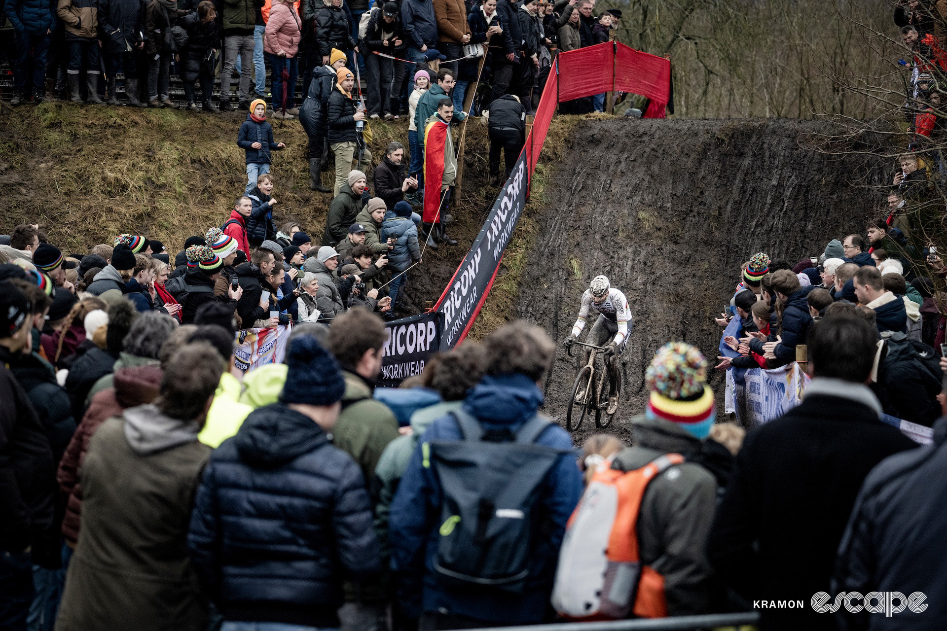 Wide shot of Mathieu van der Poel and the crowd in front of a muddy bank during cyclocross World Cup Maasmechelen.