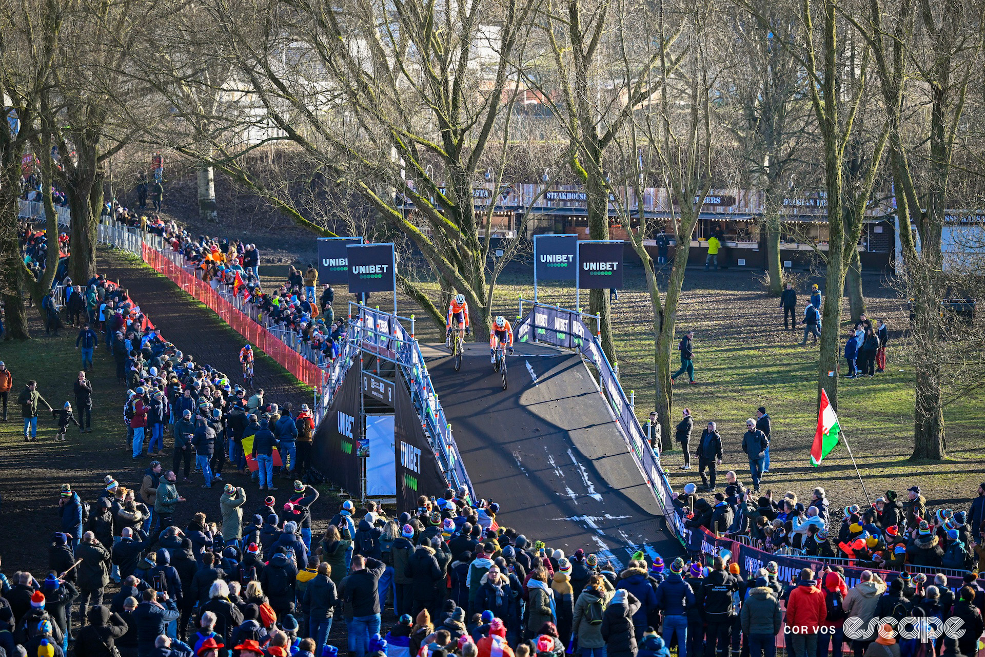 Fem van Empel and Puck Pieterse traverse the bridge a few seconds ahead of Lucinda Brand during the 2025 elite women's cyclocross World Championships.