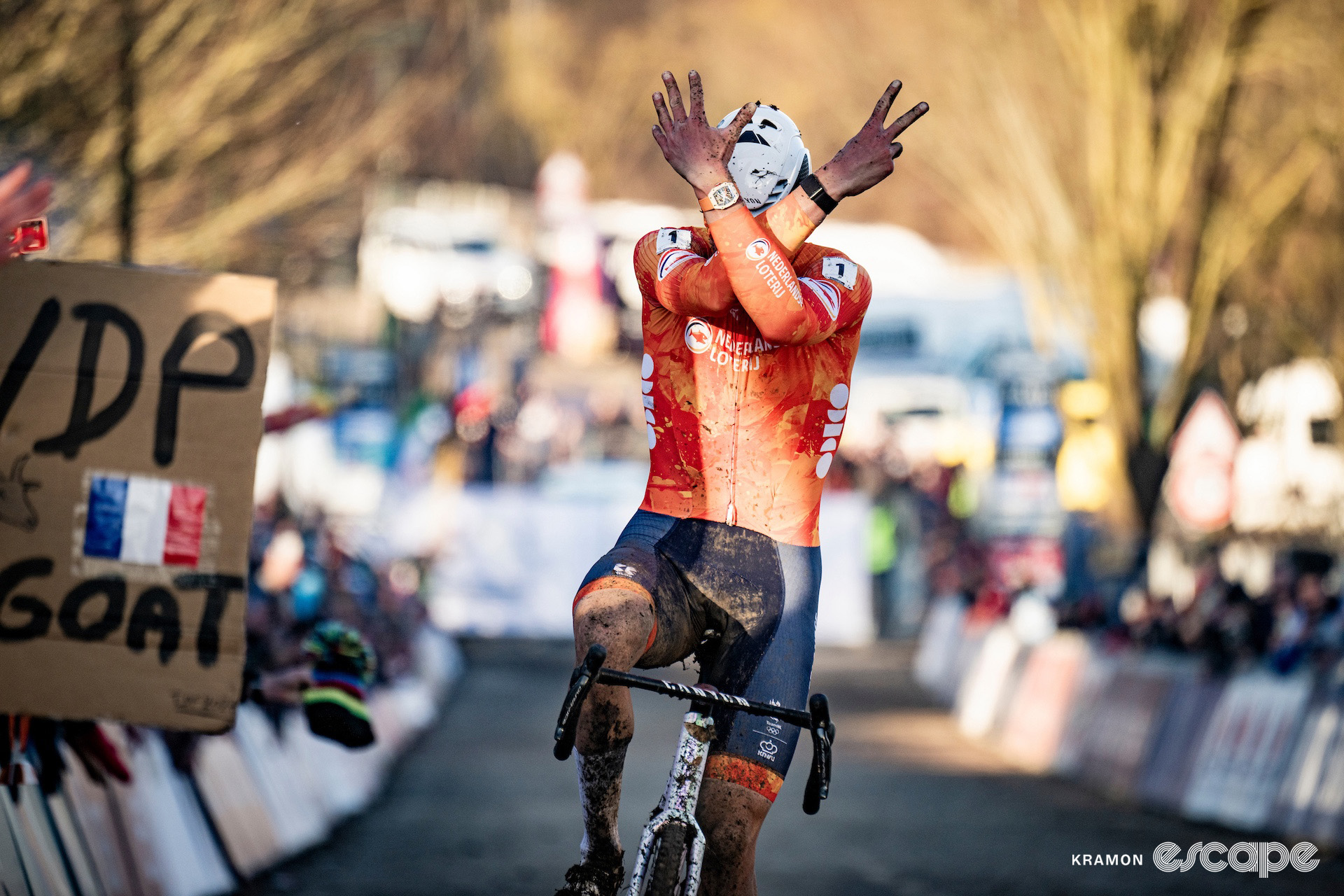 Mathieu van der Poel crosses the finish line with his forearms crossed before his face, seven fingers held up to celebrate seven elite world titles at the 2025 cyclocross World Championships.