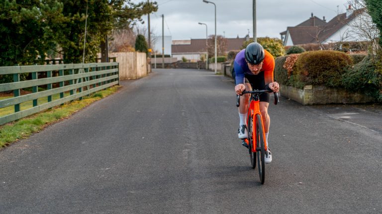 Ronan Mc Laughlin rides in an aero tuck on a normal road bike.