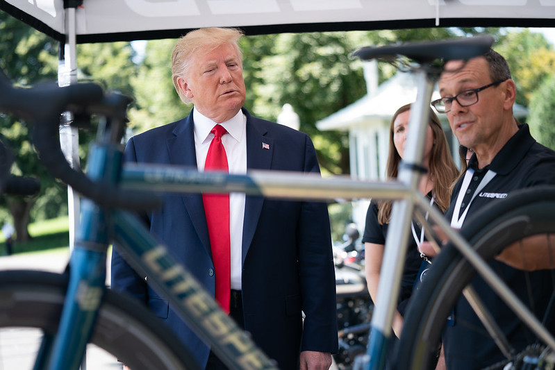 Donald Trump looks at a high-end bicycle that is being shown to him at an exhibition of US-made products.