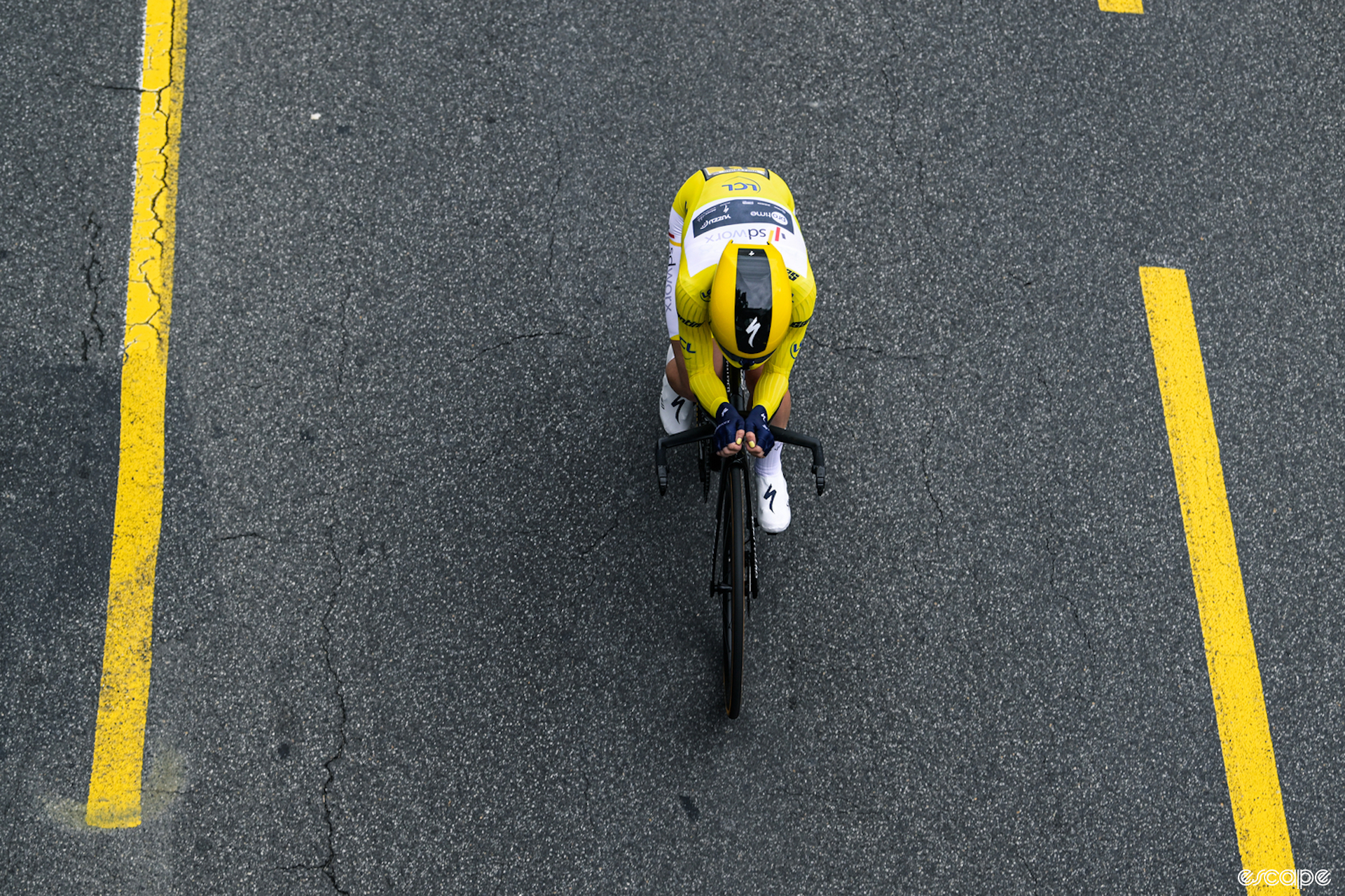 Demi Vollering rides the time trial at the Tour de France Femmes. The view is from above, looking down at her clad in the yellow skinsuit of overall leader.