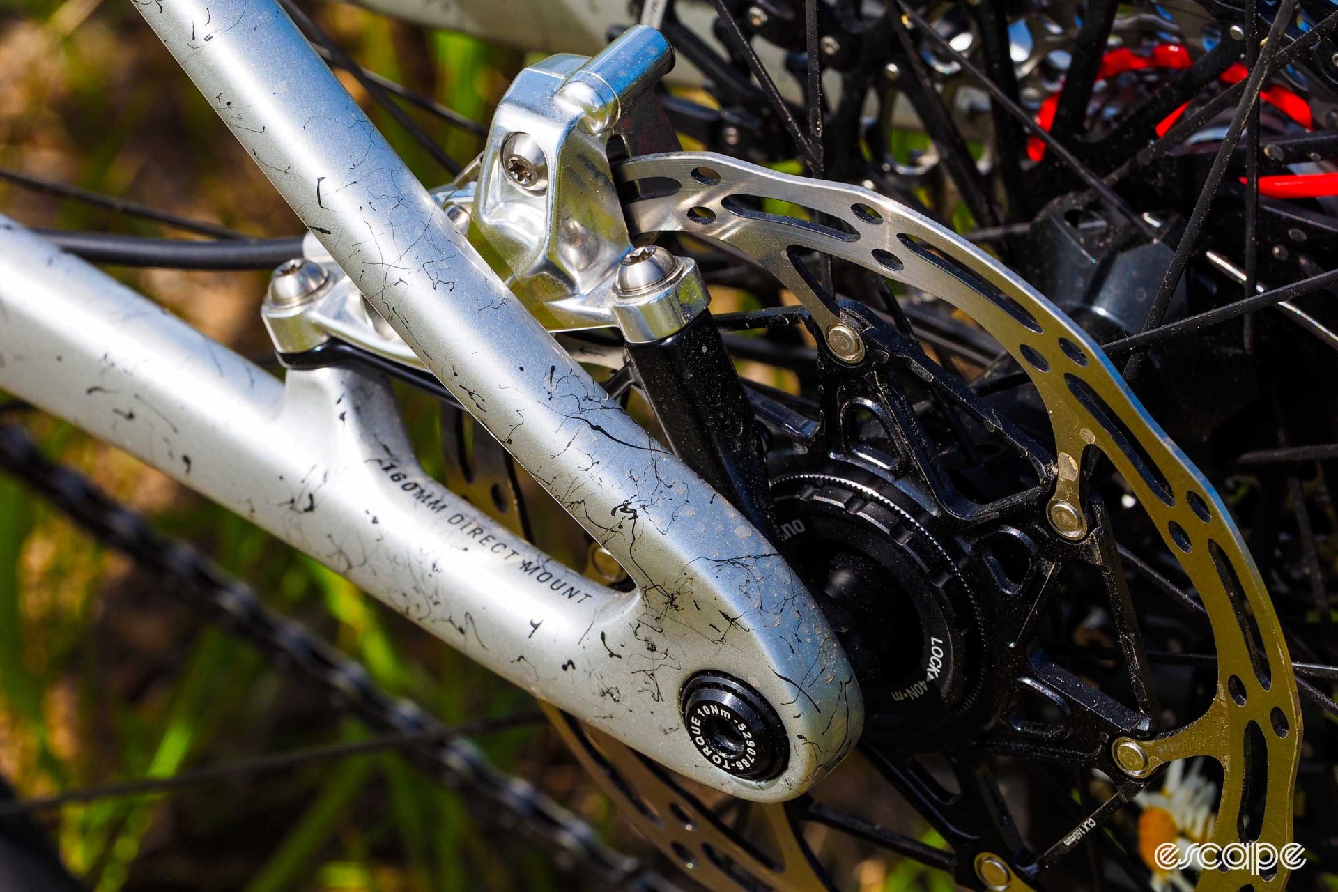 A closeup of a silver SRAM Level rear four-piston brake caliper, which is attached to a separate mount that doesn't touch the seatstay.