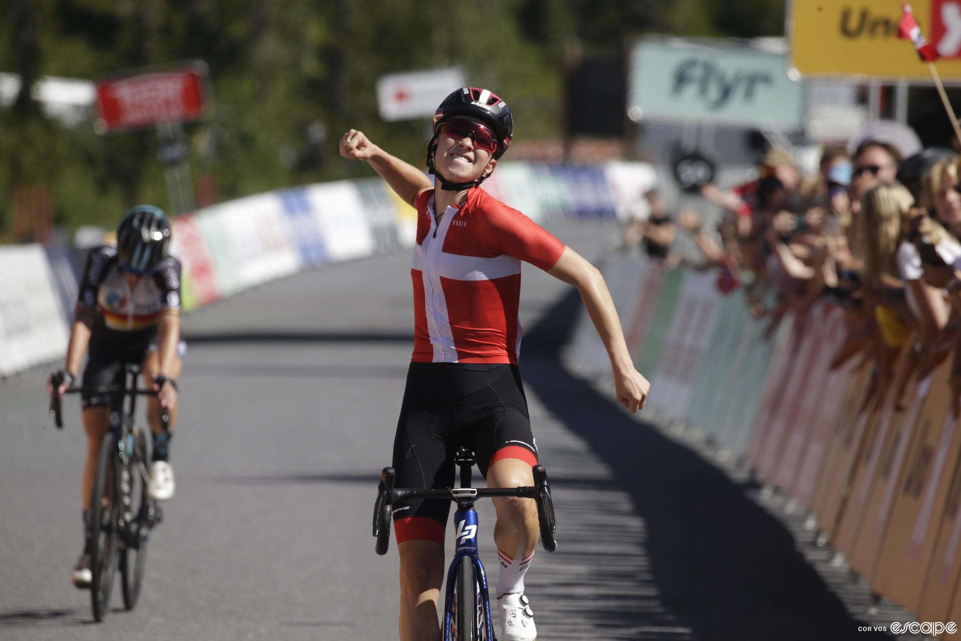 Cecilie Uttrup Ludwig wins stage 5 of the 2022 Tour of Scandinavia. She's wearing the white-cross-on-red of the Danish national champion and punches the air as she crosses the line solo.