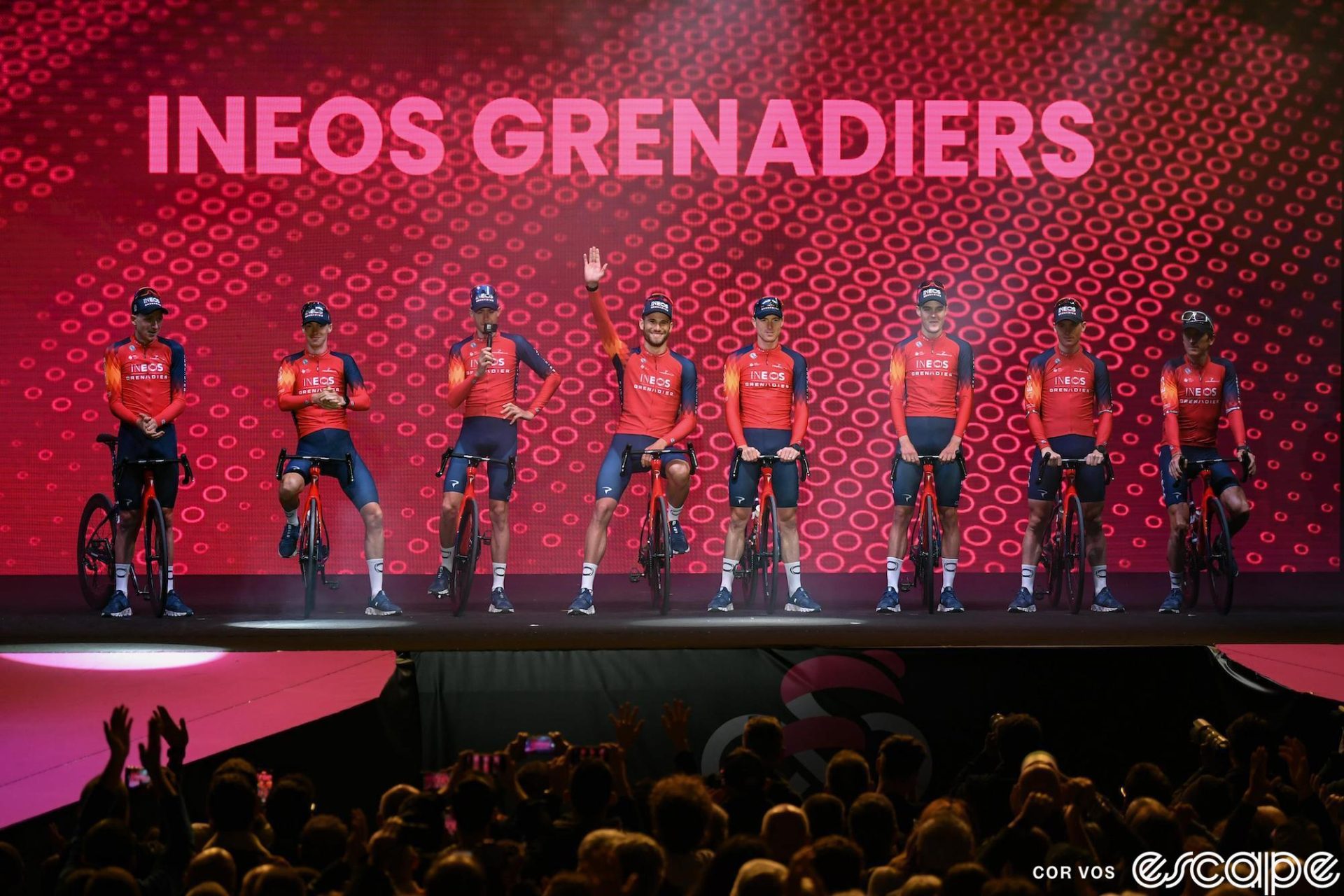 The Ineos Grenadiers team is shown at the 2023 Giro d'Italia teams presentation. The eight riders are on stage, flanked around Italian star Filippo Ganna at center. At far left is Tao Geoghegan Hart, the 2020 Giro winner, and Geraint Thomas is far right. Of the eight riders shown, two are confirmed to be leaving, and three others may.