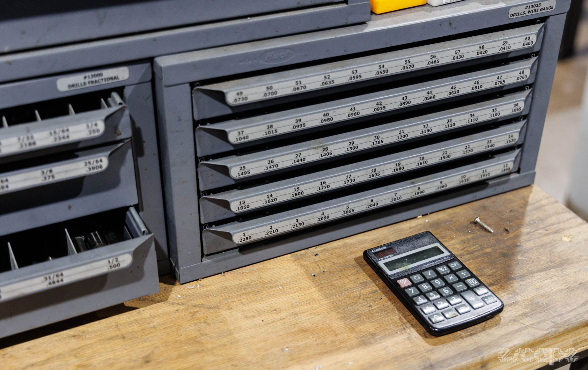 A small parts cabinet on a bench features rows of drawers with neat numbers and a calculator.
