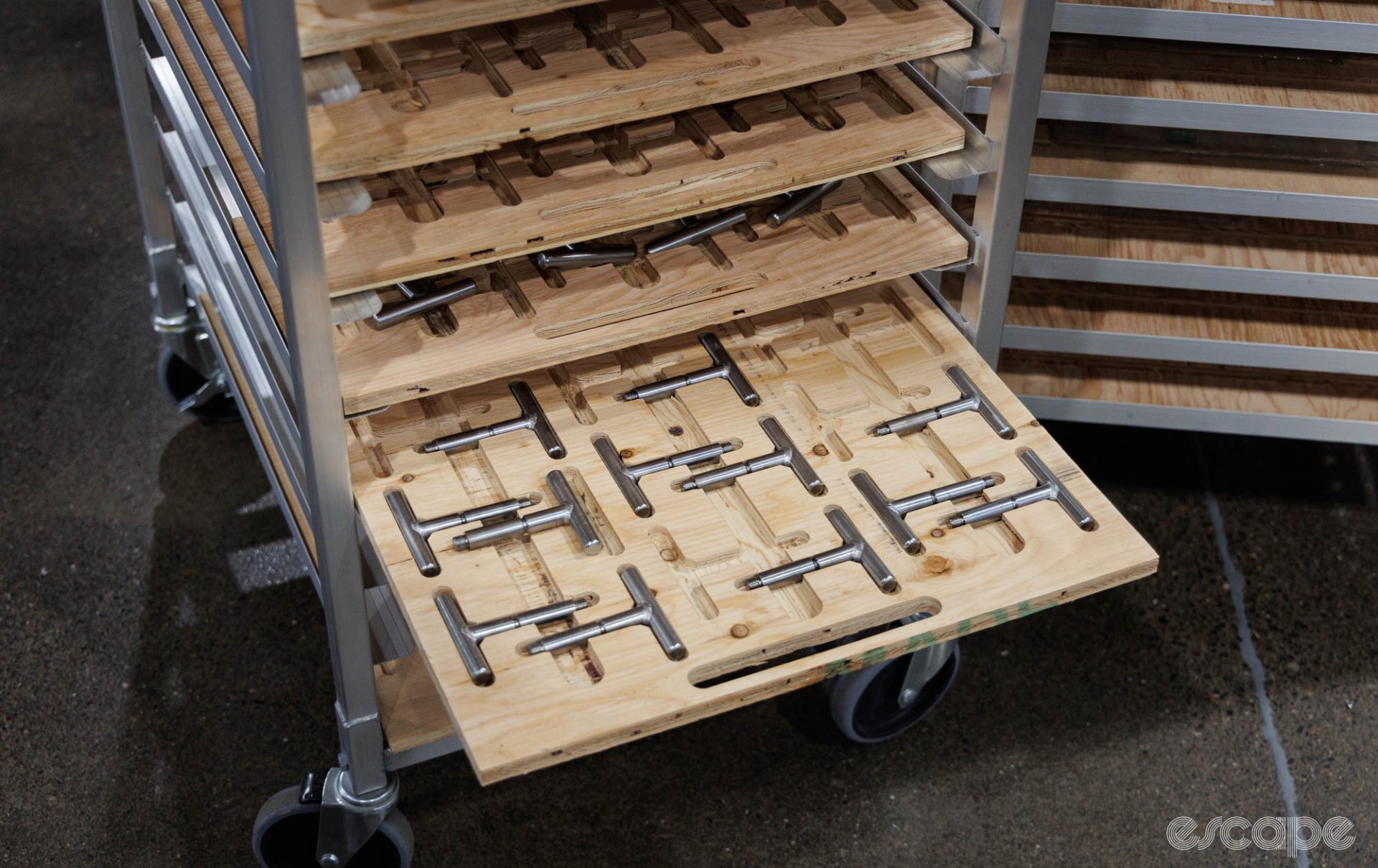 A rolling rack features rows of wood trays with cutouts to fit specific tools.