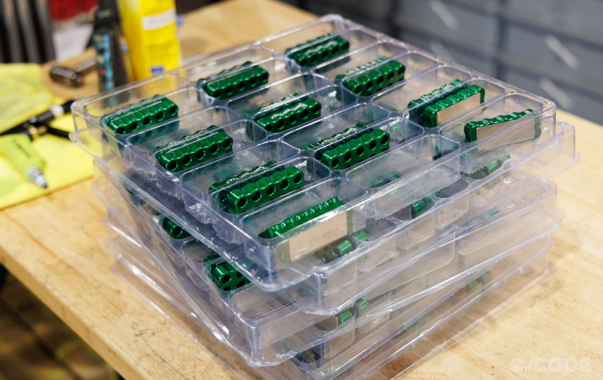 Trays of magnetic bit holders in bright green sit on a bench.
