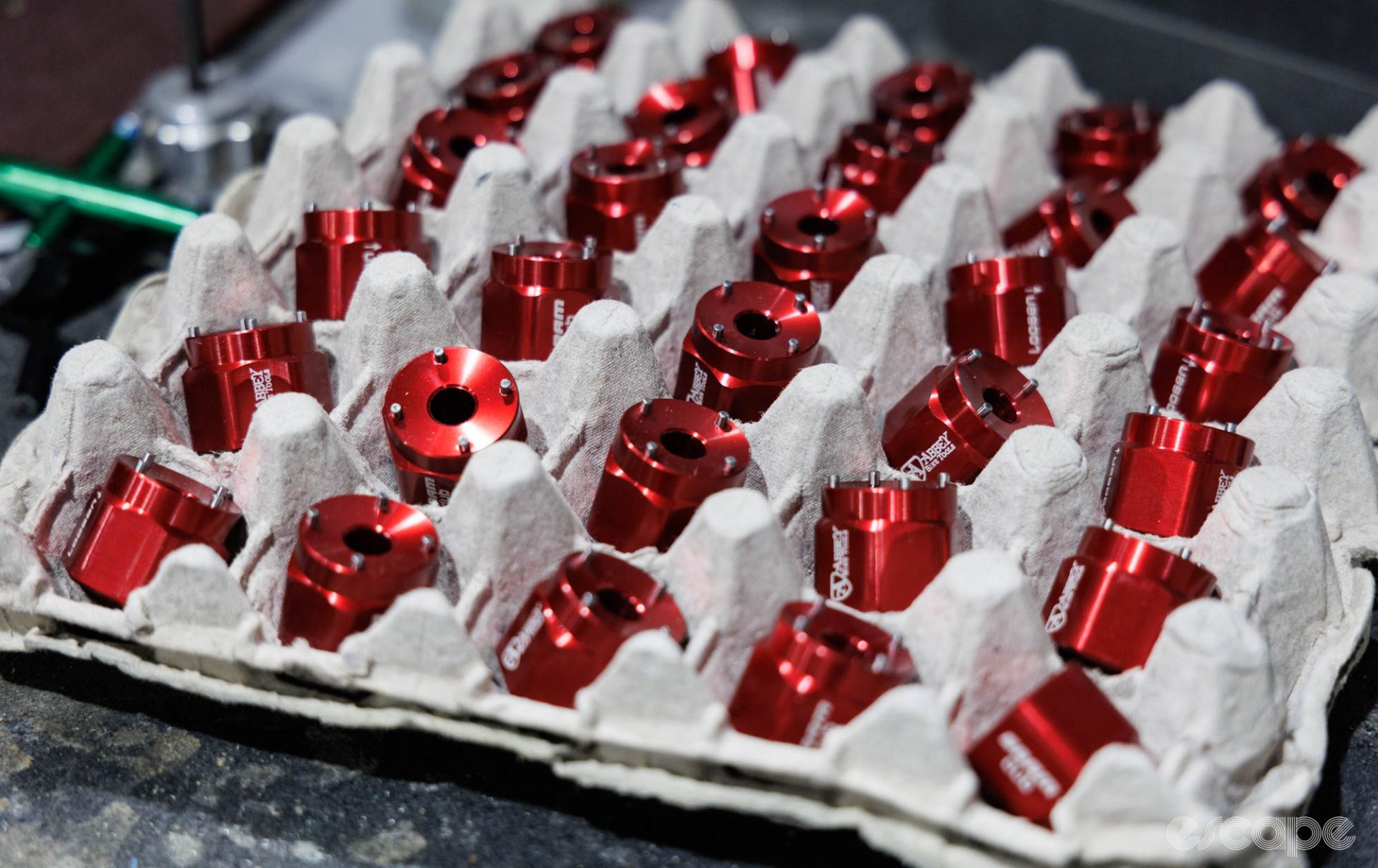 A tray of red-anodised DUB crank cap tools with the Abbey logo.