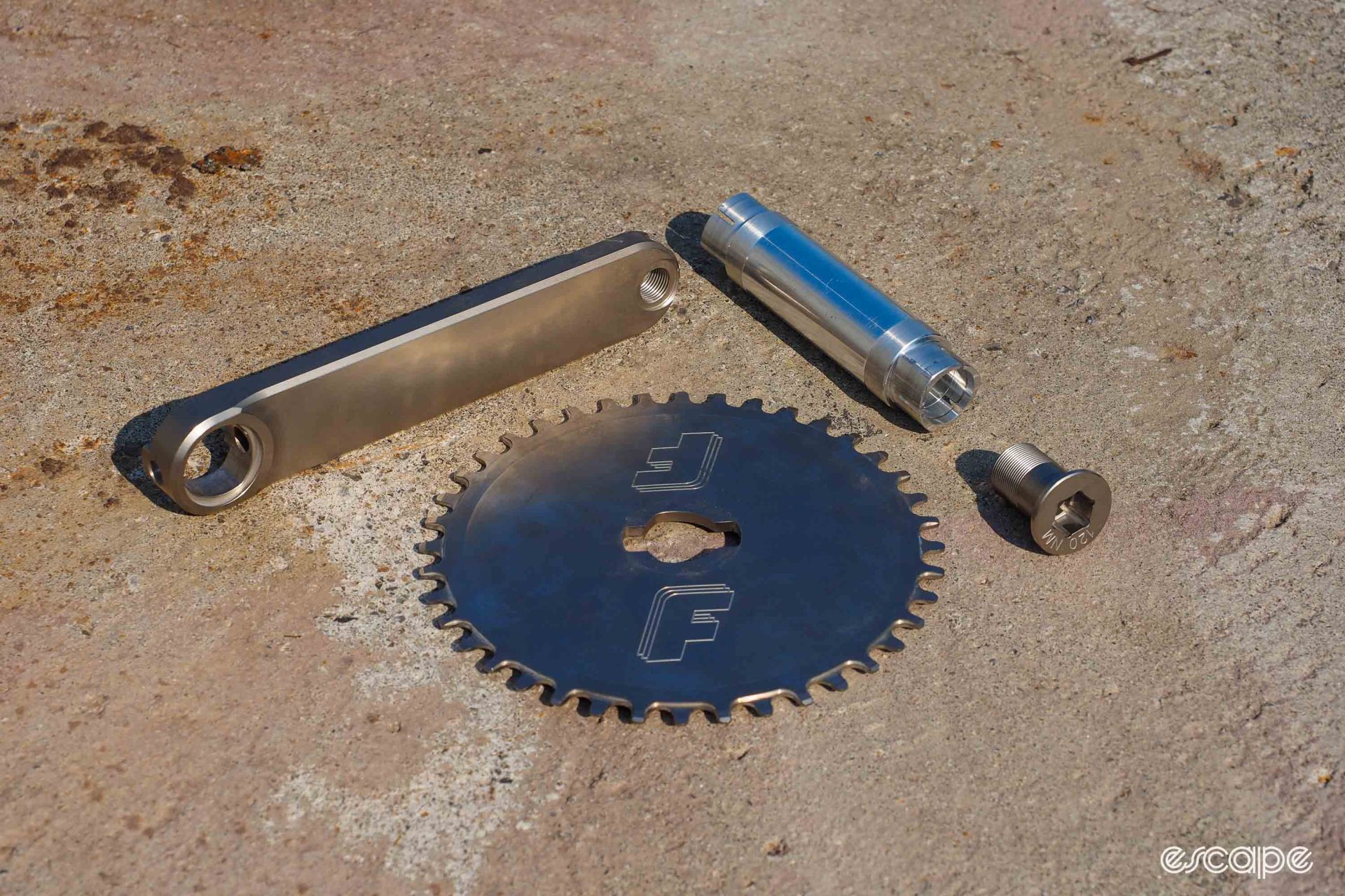 Detail shot of disassembled crank, chainring, and bottom bracket spindle.