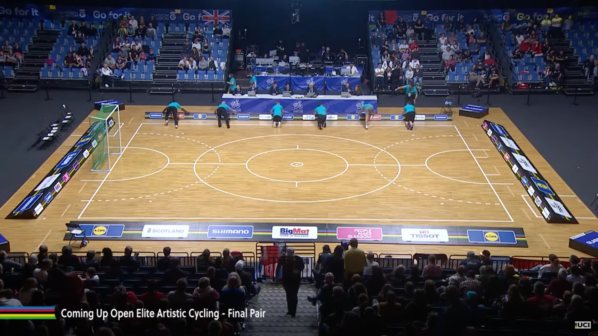 Youtube screenshot of Glasgow 2023 volunteers preparing the artistic cycling playing field.