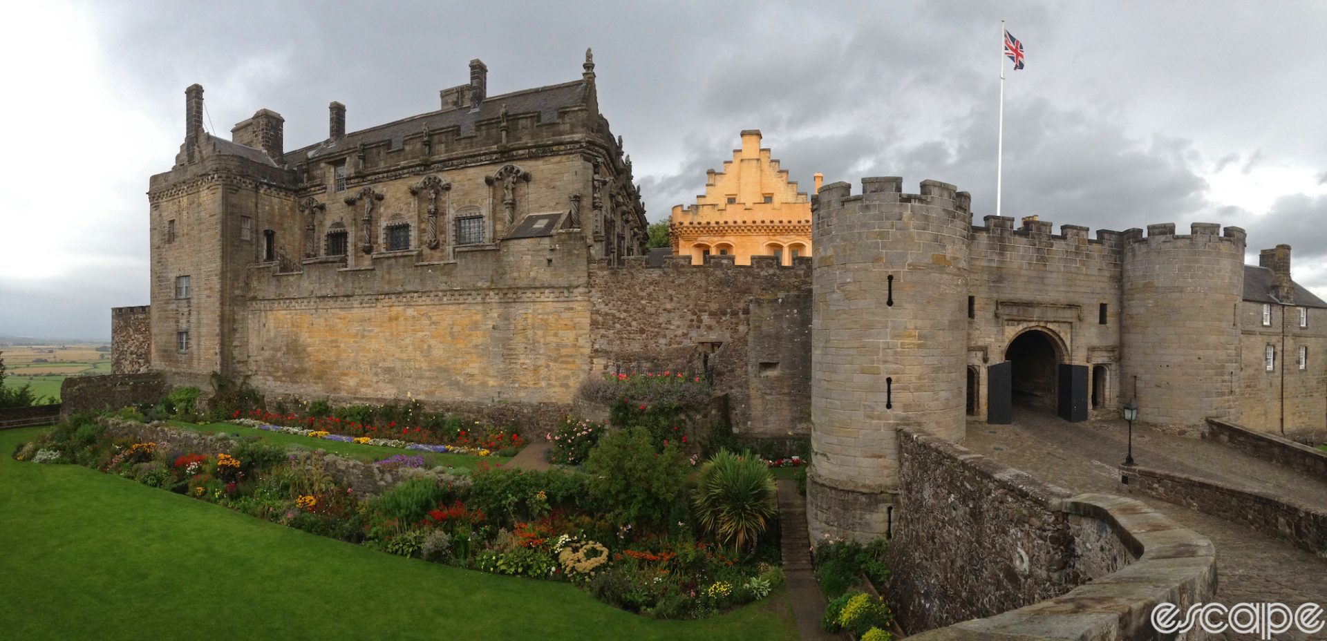 A panoramic shot of Stirling Castle in soft light, showing the castle proper and a large entrance gate with round guard towers.
