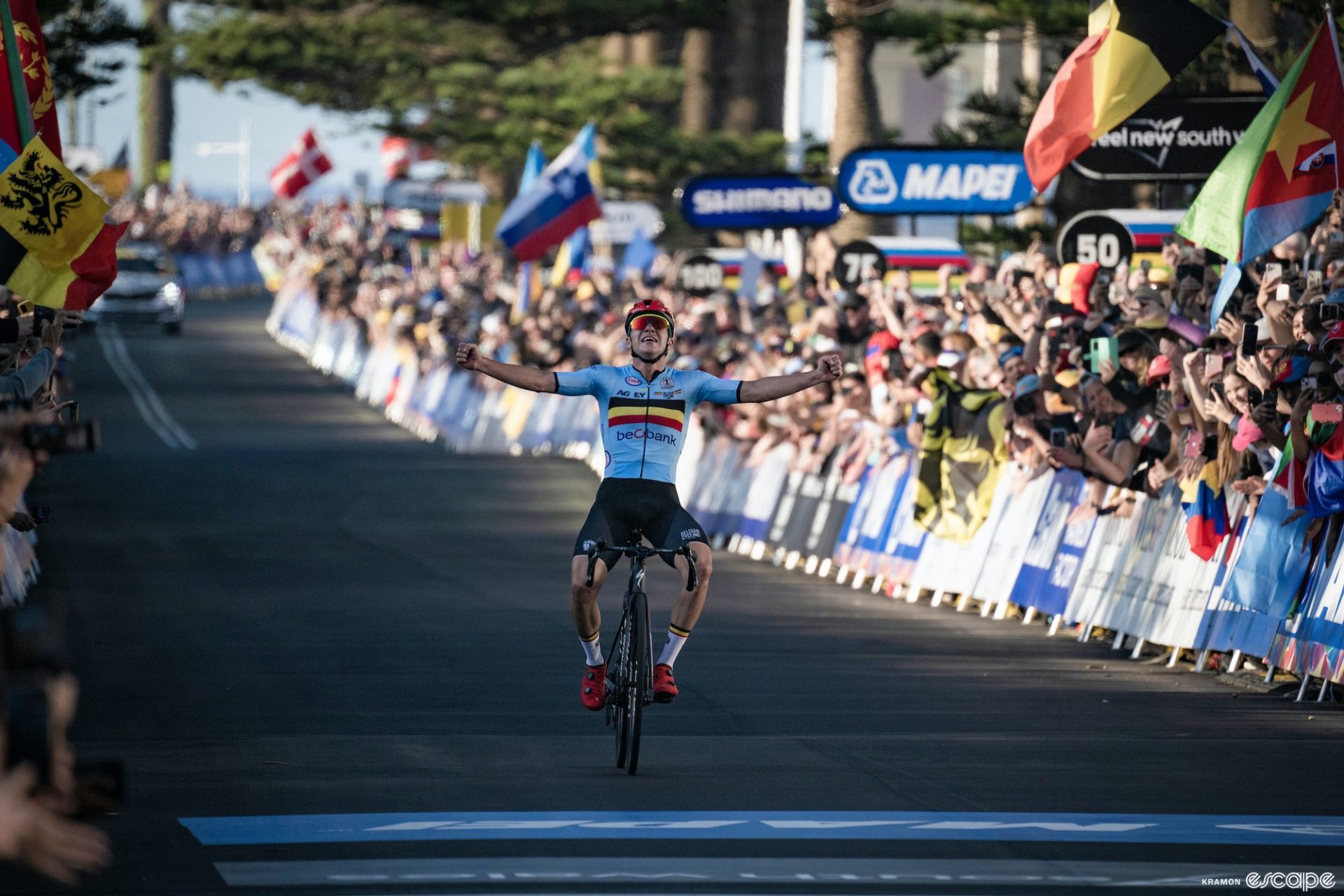 Remco Evenepoel crosses the finish line alone, arms held wide to his sides, as he wins the 2022 World Championship road race in Wollongong, Australia.