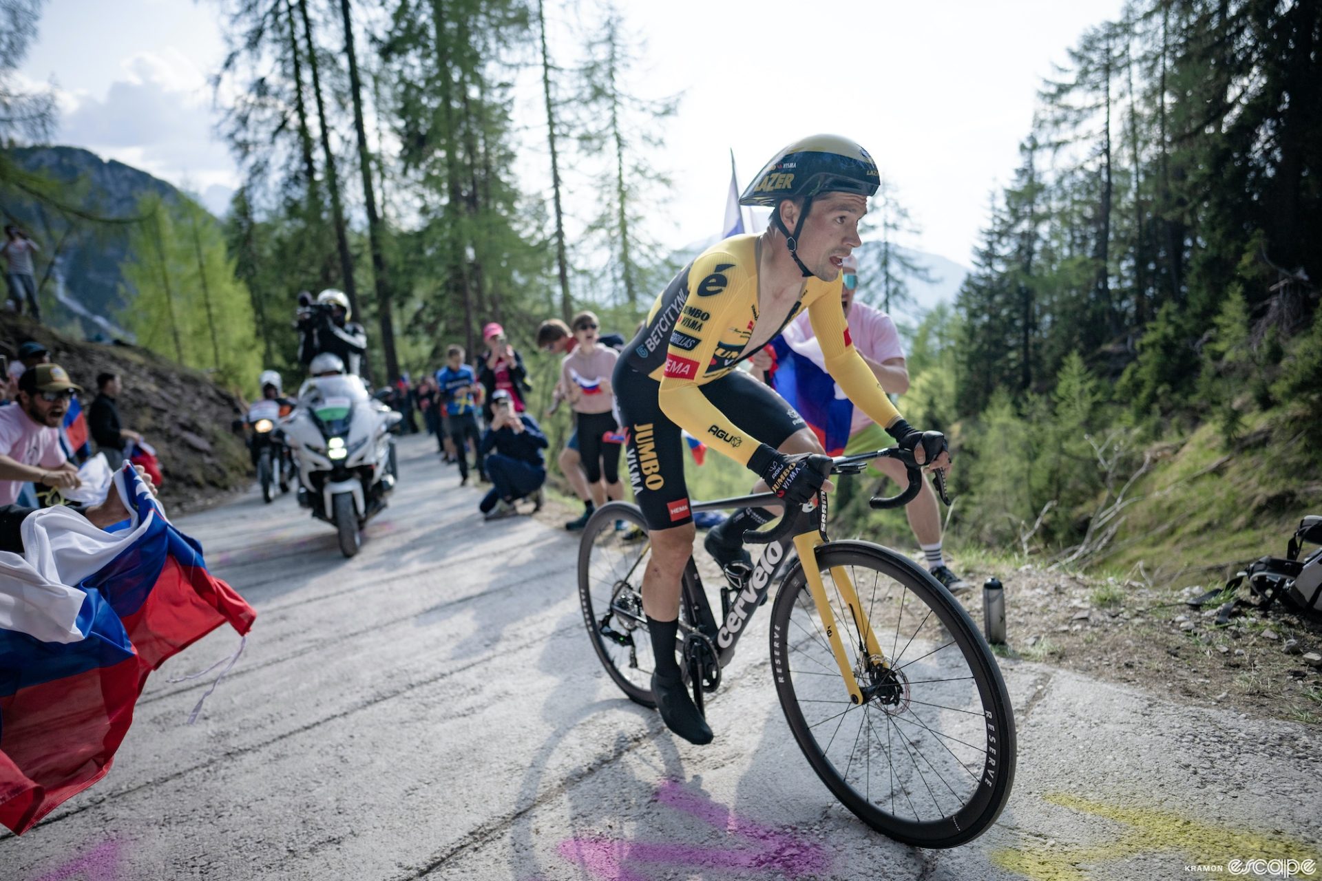 Primož Roglič climbs Monte Lussari in the stage 20 time trial at the Giro d'Italia. He's on a section of road so deep it has traction cuts in the pavement, and fans are waving the Slovenian flag at him.