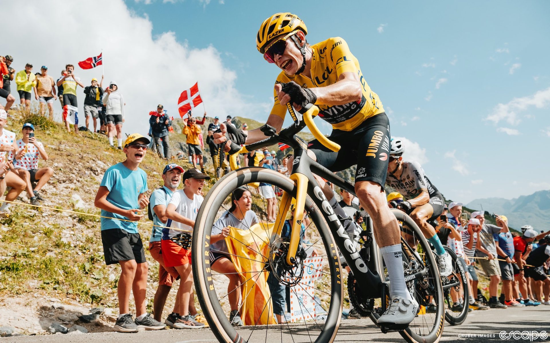 Jonas Vingegaard races on stage 17 of the Tour de France, cheered on by roadside fans while he climbs in the yellow jersey of race leader.