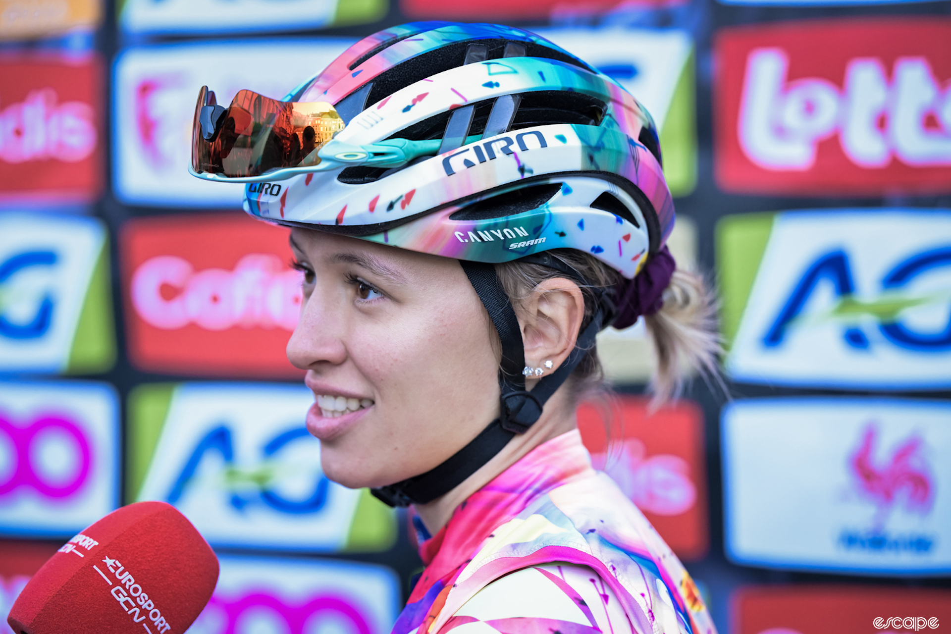 Kasia Niewiadoma talks to the press at la Fleche Wallonne Femmes. She's in the distinctive pink and white kit of her Canyon-SRAM team, with sunglasses tucked into the vents of her helmet, as she faces a Eurosport microphone.