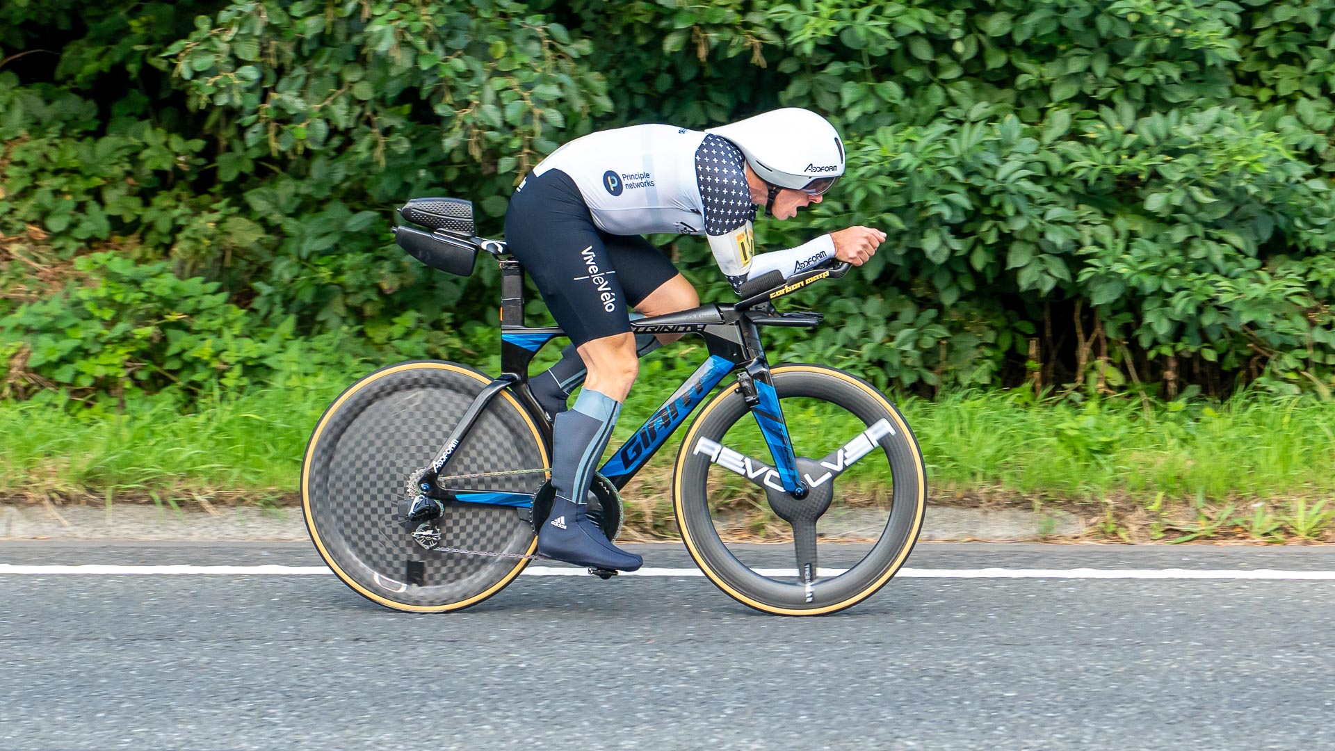The photo shows Adam Duggleby racing the UK National Ten mile time trial with calf fairings under his overshoes and two aer bottles at the rear of his saddle.