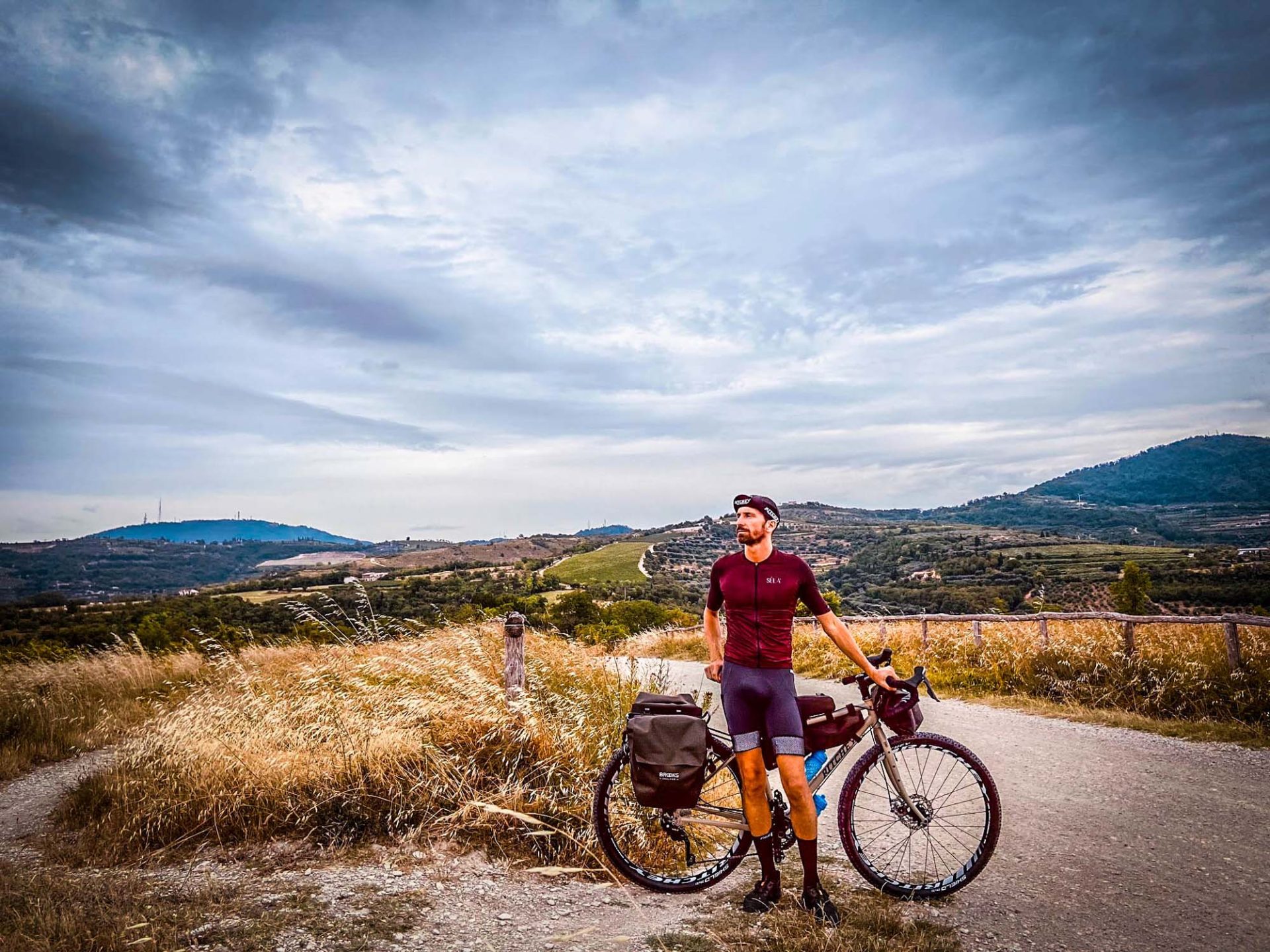 Lazzarin poses with his bike in front of a hilly, Italian town. 