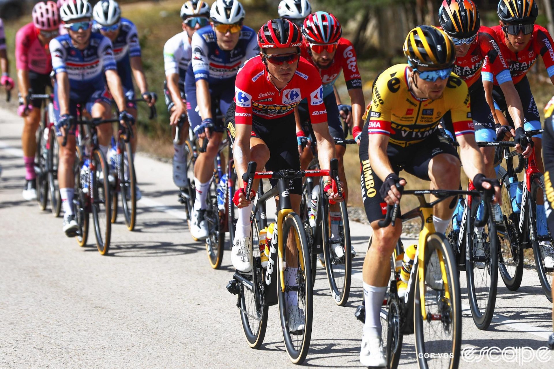 American Sepp Kuss sits on the wheel of teammate Primož Roglič on stage 11 of the 2023 Vuelta a España. Behind, riders from Bahrain Victorious and Soudal Quick-Step follow in the pack. The pace and body language are relaxed on what was not a stressful day of racing.