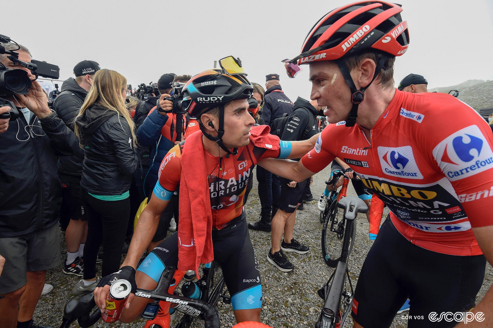 Mikel Landa and Sepp Kuss share a word at the finish of stage 17. Both have intense expressions as they put a hand on each other's shoulder.